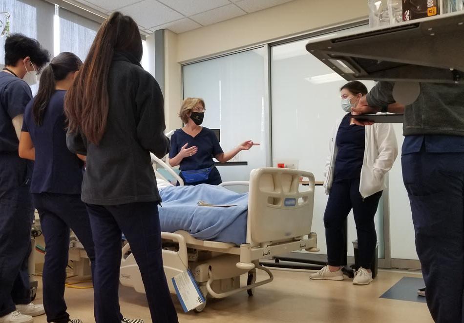 TVFSON护理指导老师带领一班学生, 都穿着蓝色的工作服, 在护理模拟实验室.