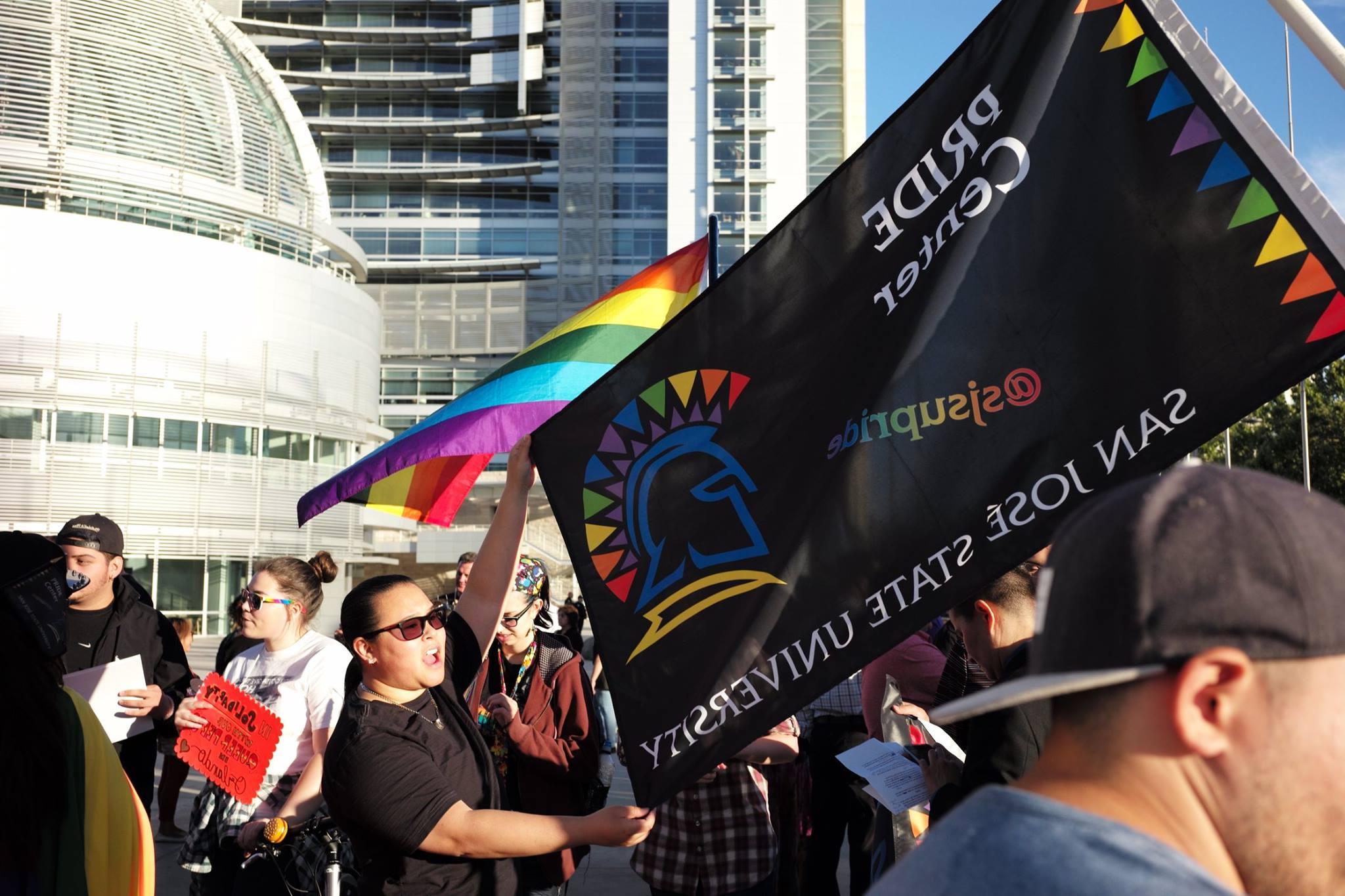 一面黑色的旗帜，上面有彩虹色的菠菜网lol正规平台斯巴达和骄傲中心的字样.